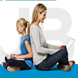 Mum and daughter leaning back to back looking at laptops
