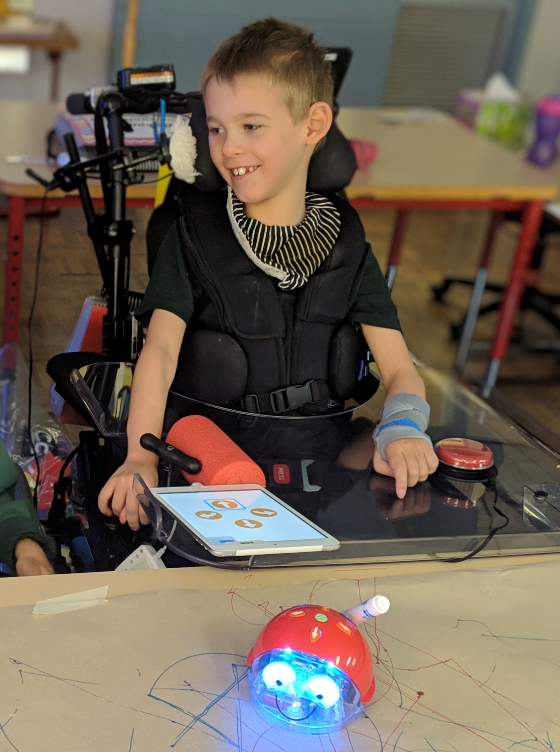 Image of a primary school boy playing with a blue bot and a tablet