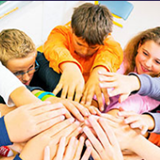 Group of children putting their hands in the middle of a circle
