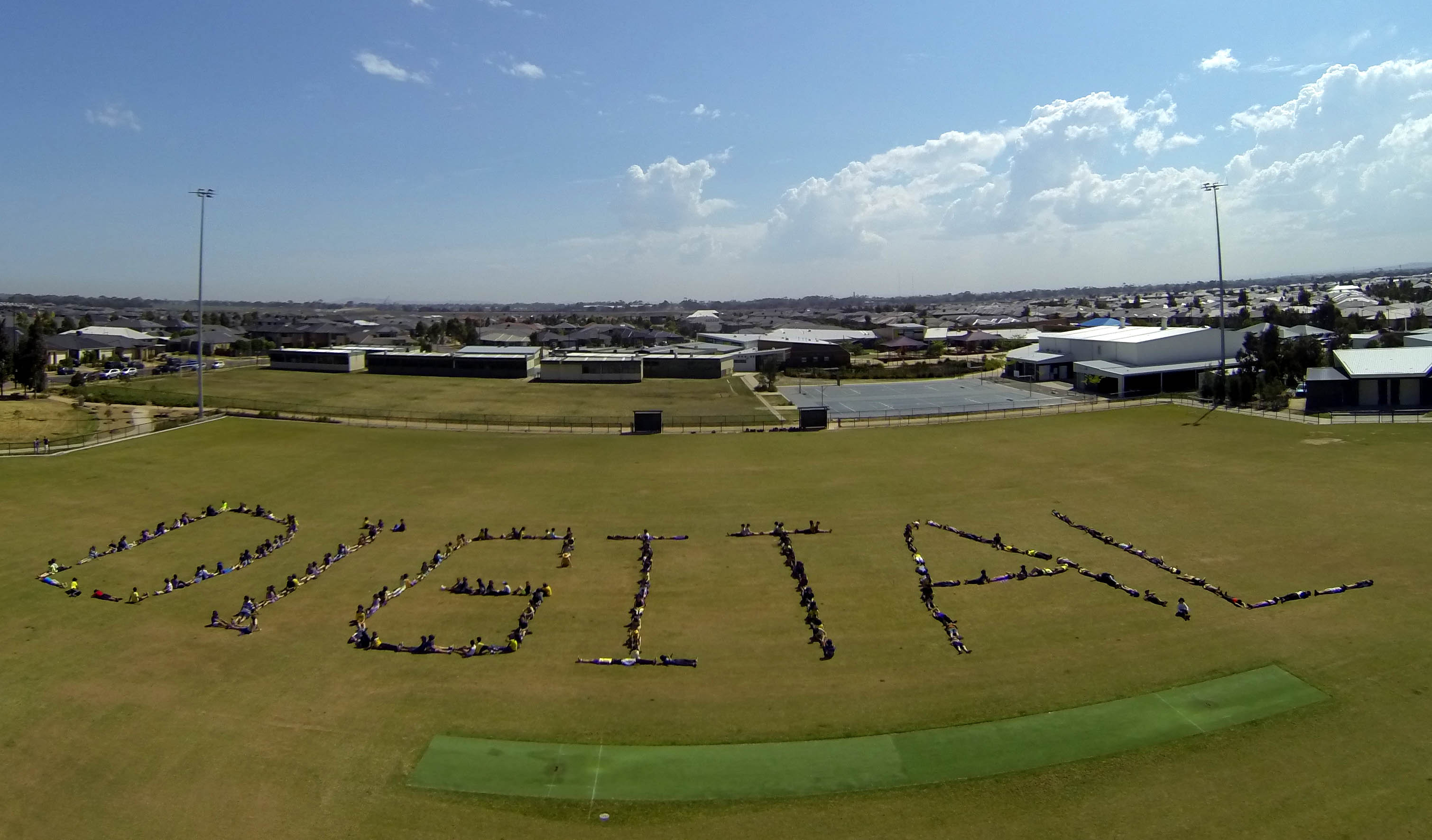 PCC students form the shape of the word Digital on their oval