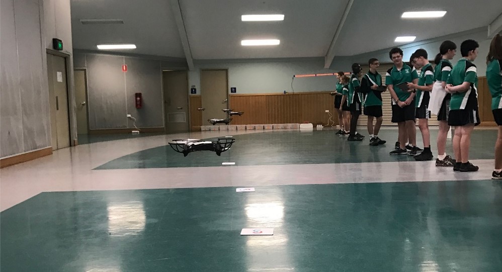 Students using drones in a gymnasium