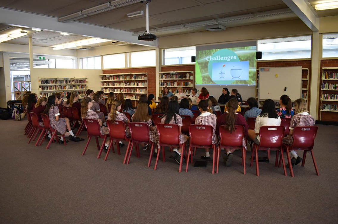Image of children sitting on chairs in a classroom looking at a powerpoint