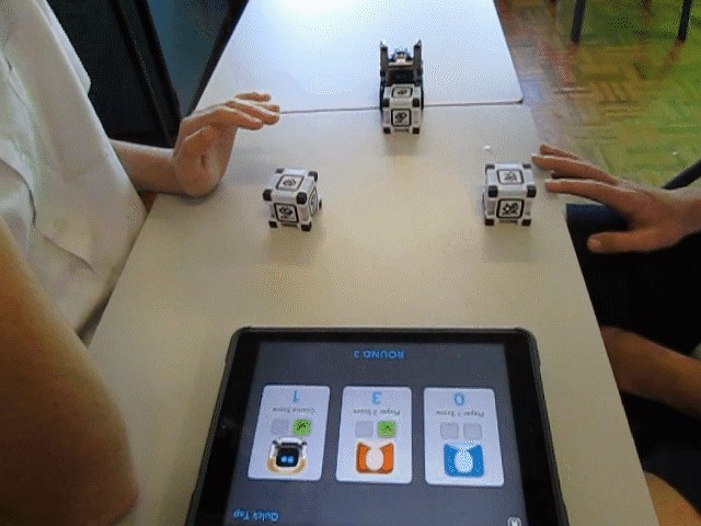Image of two two students using the Cozmo Robot by controlling it with an iPad.